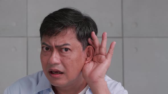 Asian senior man couldn't hear the cause of his deafness. alt