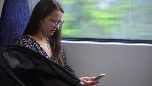 Close Shot of Young Attractive Ukraine Female in Glasses Sitting on Moving City Metro Train alt