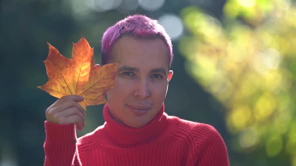 Young Gay Is Posing Outdoors, Smiling and Holding Dry Leaf of Maple, Closeup Portrait of Homosexual alt