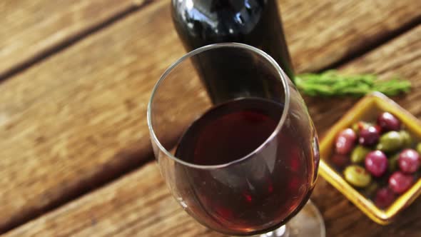 Glass of red wine, olives and rosemary on wooden board alt