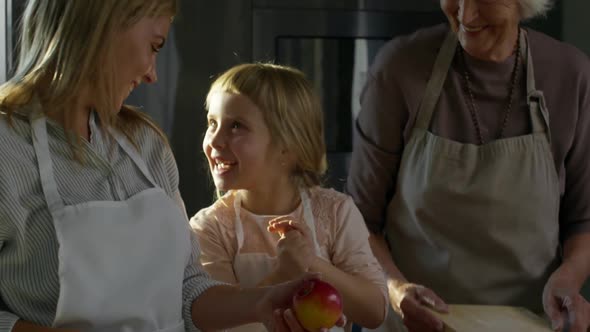 Playful Girl Clapping Hands while Cooking with Mom and Grandma alt