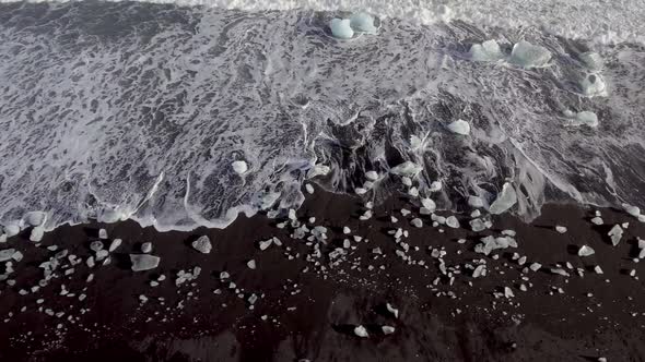 Aerial view of black sand beach with iceberg ice pieces on the shore also cal