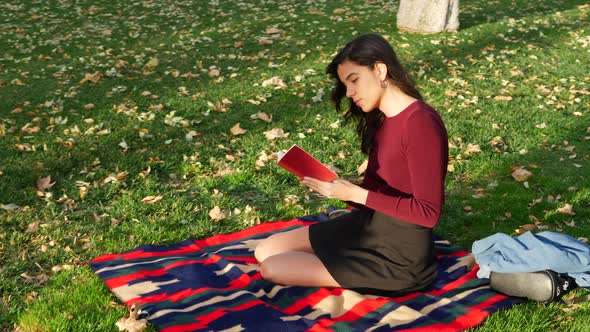 A young woman school girl reading a book on a campus lawn or outdoor park SLOW MOTION. alt