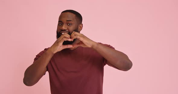 Young African American Man Make Heart Gesture Isolated on Pink Background alt