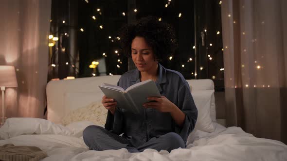 Woman Reading Book Sitting in Bed at Night