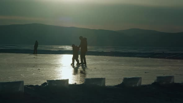 Father and Son Go Ice Skating on Frozen Lake at Sunset in Winter