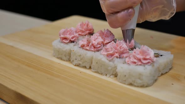 Detail Sushi Chef Squeezes Pink Lava Sauce Onto Cream Cheese Rolls