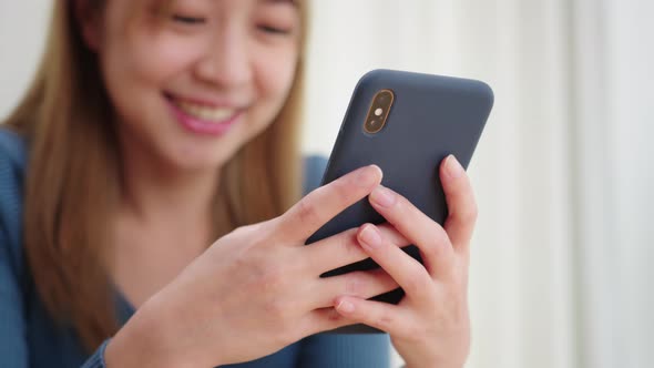 Young Asian Woman using mobile phone enjoying searching, surfing on the internet on a phone