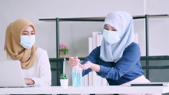 businesswomen wear protective masks and clean hands with sanitizer alcohol gel during work alt