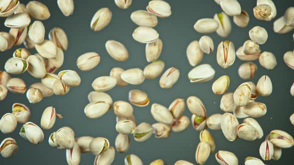 Super Slow Motion Shot of Flying Pistachios After Being Exploded on Grey Background at 1000Fps alt