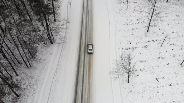 Classic Gray Car Driving Through the White Winter Snowy Forest on Country Road alt