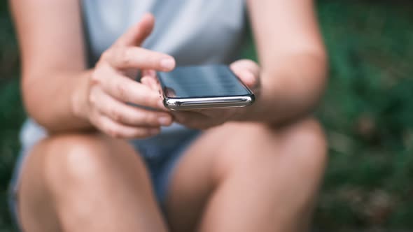Close Up of Young Woman Hands Using and Holding Smart Phone Scrolling Up and Down on Touchscreen alt