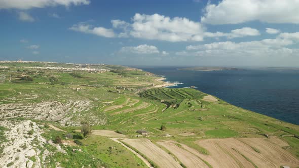 AERIAL: Flying Over Ta Cenc Cliffs Greenery Plains near Beautiful Calm Mediterranean Sea