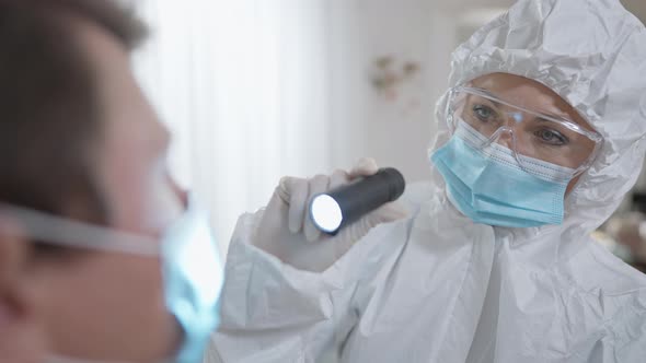 Portrait of Focused Caucasian Nurse Performing Medical Examination with Flashlight alt