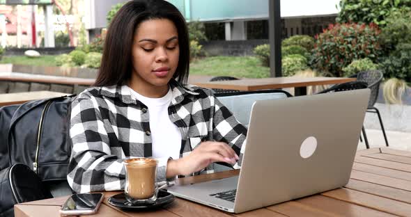 Young african american woman using laptop in cafe.