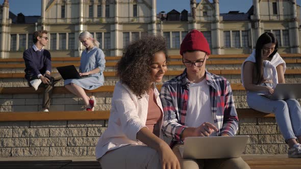 Multiethnic Friends Man and Woman Using Laptop on University Campus alt