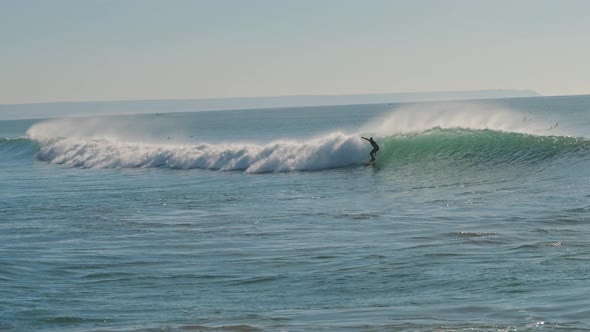 Surfer catching a big wave of the Atlantic Ocean on a beautiful sunny day alt