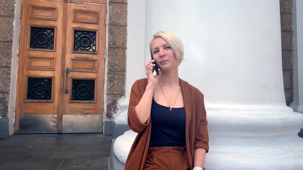 Business Woman Speaking Mobile Phone Sitting on the Background of the Columns