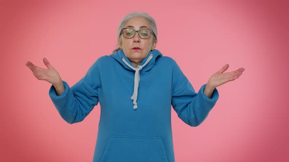 Puzzled Clueless Mature Old Granny Woman Raising Hands in Helpless Gesture Difficult Question alt