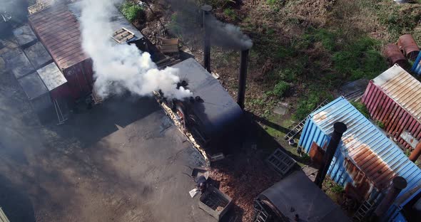 Aerial view of unrecognizable woodsmen loading a retort in charcoal production. alt