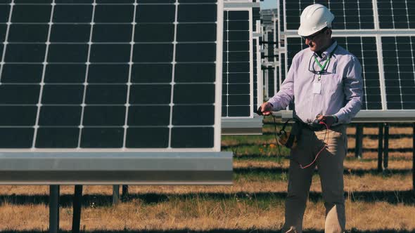 Energy Engineer Monitoring Solar Panels with His Multimeter. Solar Energy Concept. alt