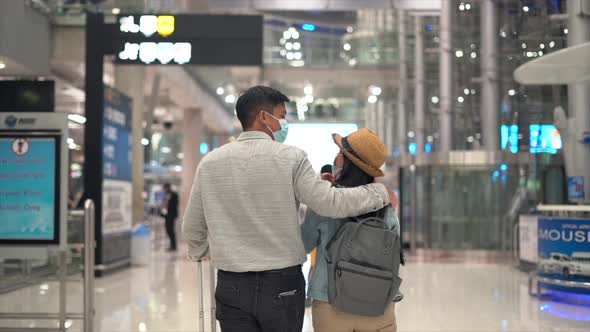 Couple Asian people walking in airport terminal waiting for  flight boarding.