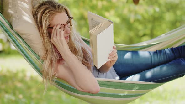 Smiling blonde woman with eyeglasses reading a book