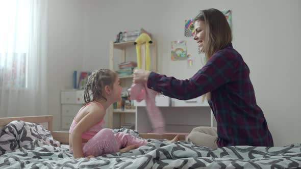 Mom Puts Her Daughter in a Sweater on the Bed alt