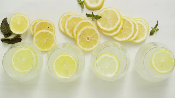 Fresh lemonade in a drinking glasses garnished with sliced of lemon and mint. alt
