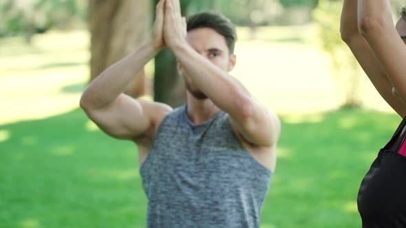Young Man and Woman Meditating in Yoga Pose at Outdoor Training in Summer Park alt
