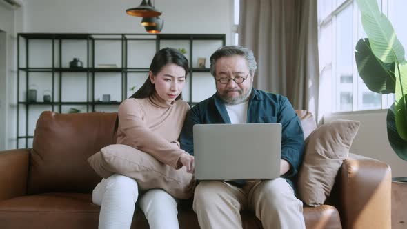 marry asian couple home finances, reviewing their bank money accounts using laptop alt