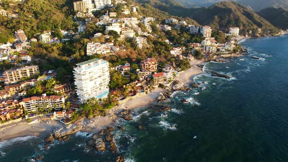 blue ocean waves crashing on the coastline beach of Playa Amapas in Puerto Vallarta Mexico at sunset alt