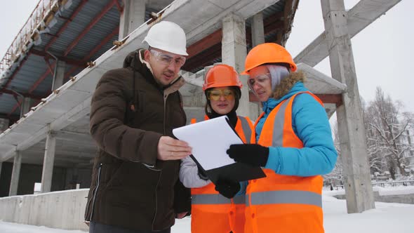 The Foreman and Two Women Inspector Winter Inspect the Construction Site alt
