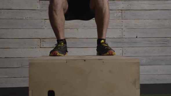 Lower half of man working out as he jumps on wood box alt