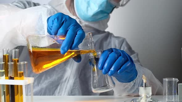 scientist working with chemical reagents and solutions pours liquid in test tube alt