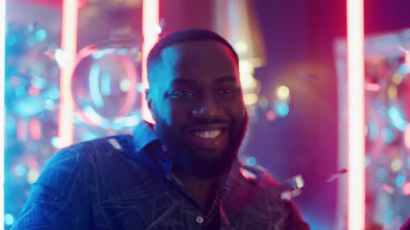 Joyful Man Dancing Under Confetti. Afro Guy Making Movements on Neon Background alt