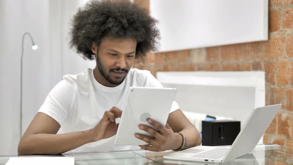 African Man Browsing Internet on Tablet alt