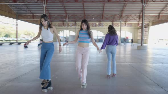 Tracking Pan of Three Girls Roller Skating Backwards Outdoors Slomo alt