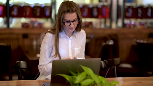 Young Girl Typing Laptop In Cafe alt