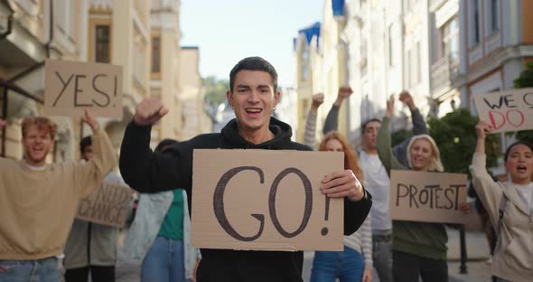 Man Activist Shows Go Poster with Multiraciaal People Protest Activists in Background alt