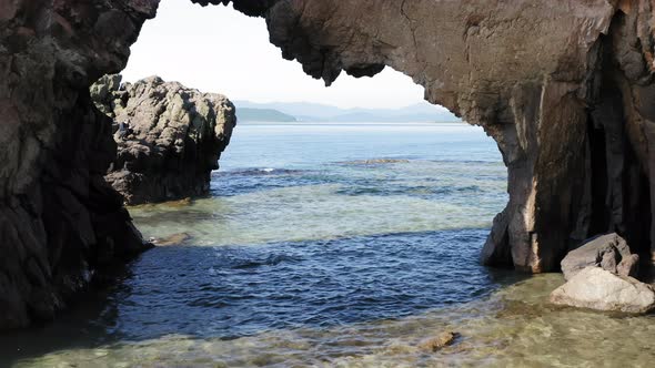 Flying a Drone Through a Natural Stone Arch on the Seashore alt