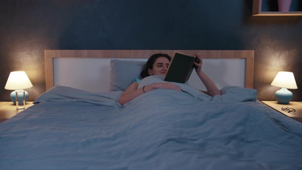 Teen Brunette Girl Lying in Bed Reading a Book and Smiling Cinematic