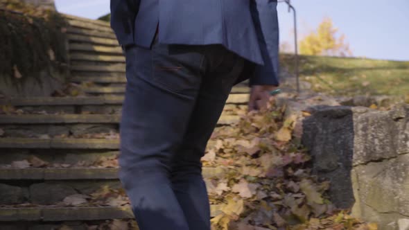 A Middleaged Handsome Caucasian Man Walks Away From a Quaint Building and Up a Stone Staircase