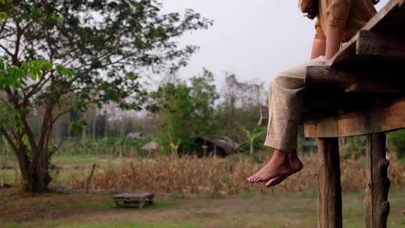 A woman sitting and chilling on wooden house balcony with nature view in countryside