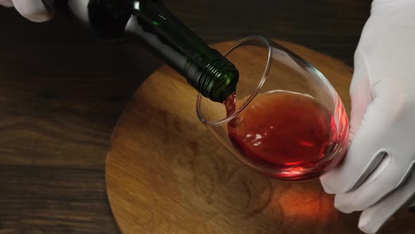 Skilled sommelier pouring red wine from bottle into Glass. 4k