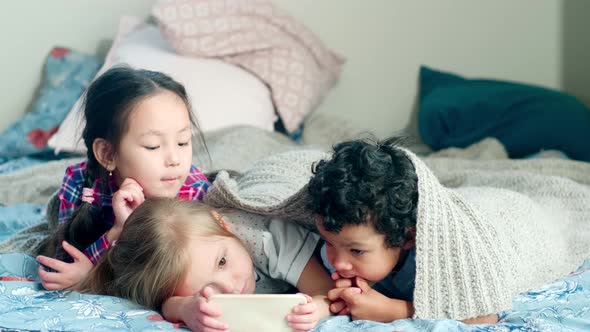 Mixed-Raced Little Friends Watching Video on Smartphone on Bed