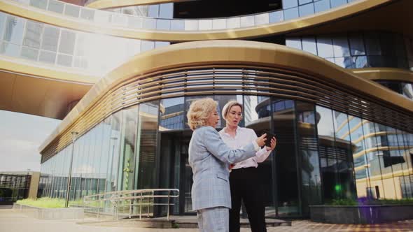 Smiling Businesswomen Having Discussion Standing in Front of Building