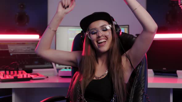 Soundwoman in Designer Glasses Cap and Headphones Enjoys Working in the Recording Studio
