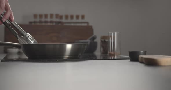 Man Flipping Steak with Tongs in Steel Pan on Kitchen Stove alt