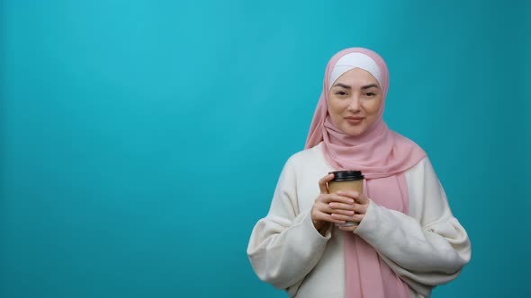 Young Muslim Woman in Hijab Hold Paper Cup of Coffee or Tea and and Dreams and Thinks